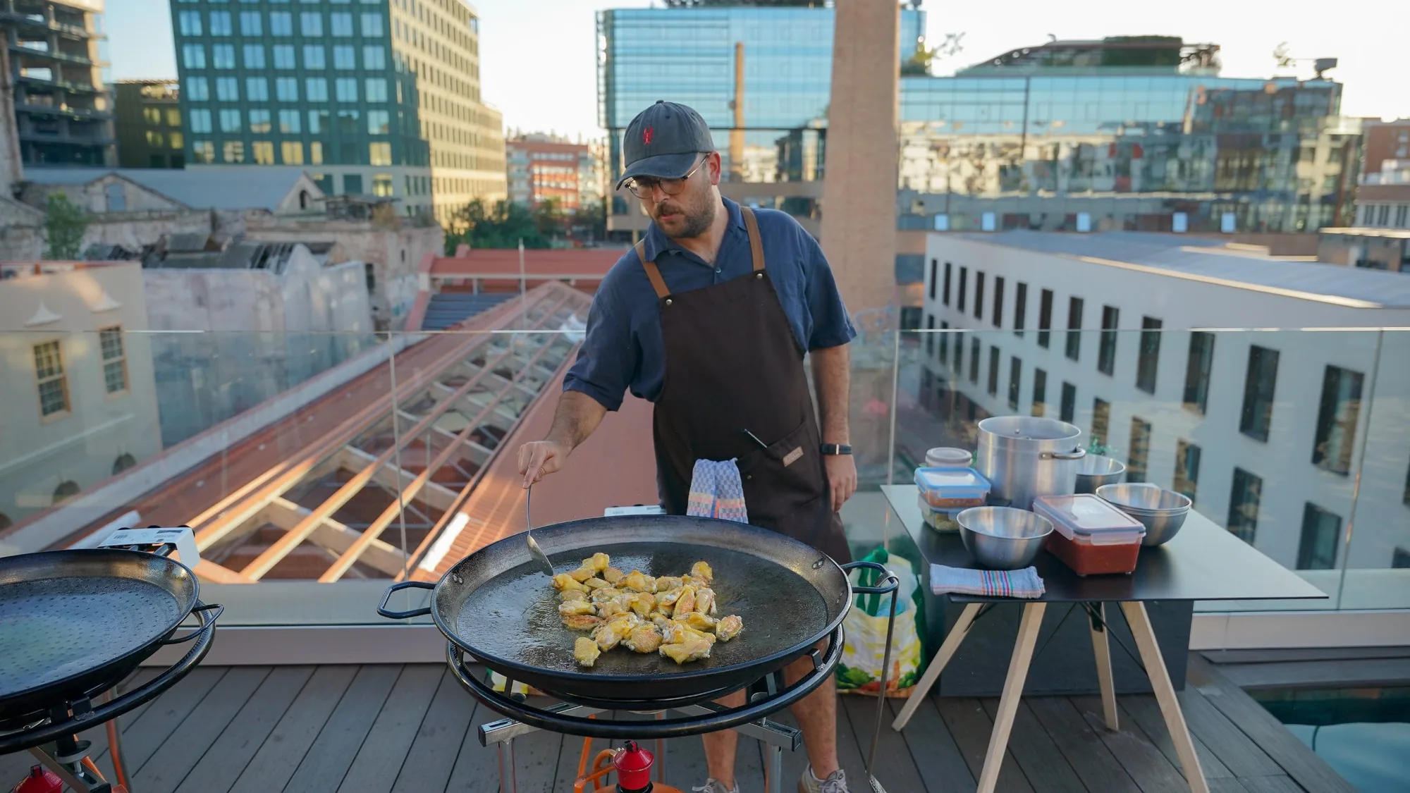 Paella being cooked on the Blau rooftop at sunset, with the Poblenou skyline behind