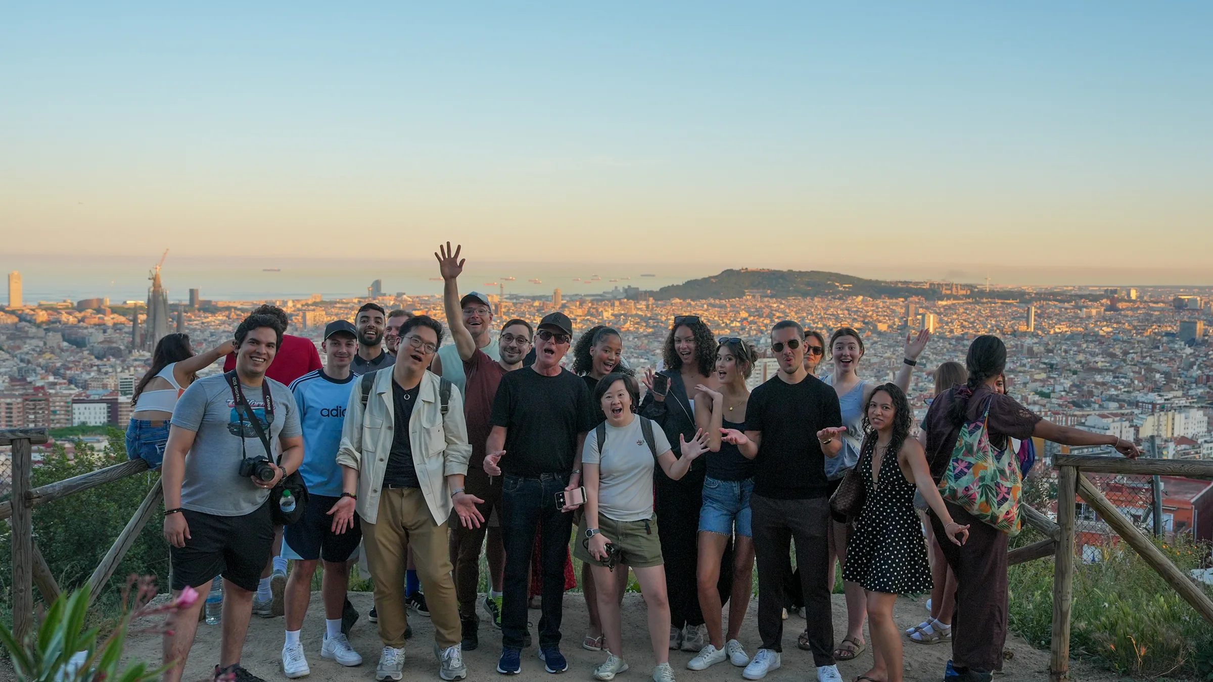 A group of Blau students waving above Barcelona at sunset, at the Bunkers del Carmel