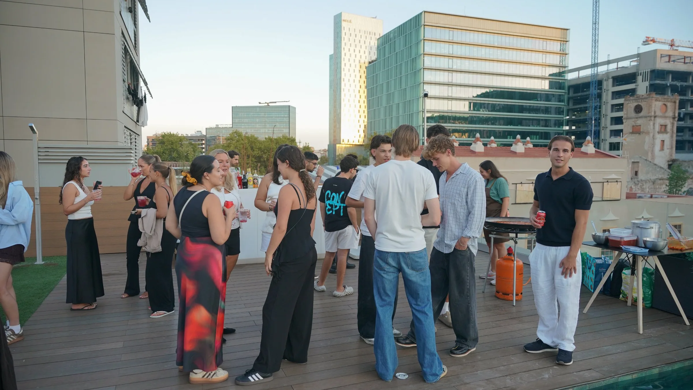 Students at an evening event on the Blau rooftop, with the Poblenou skyline behind